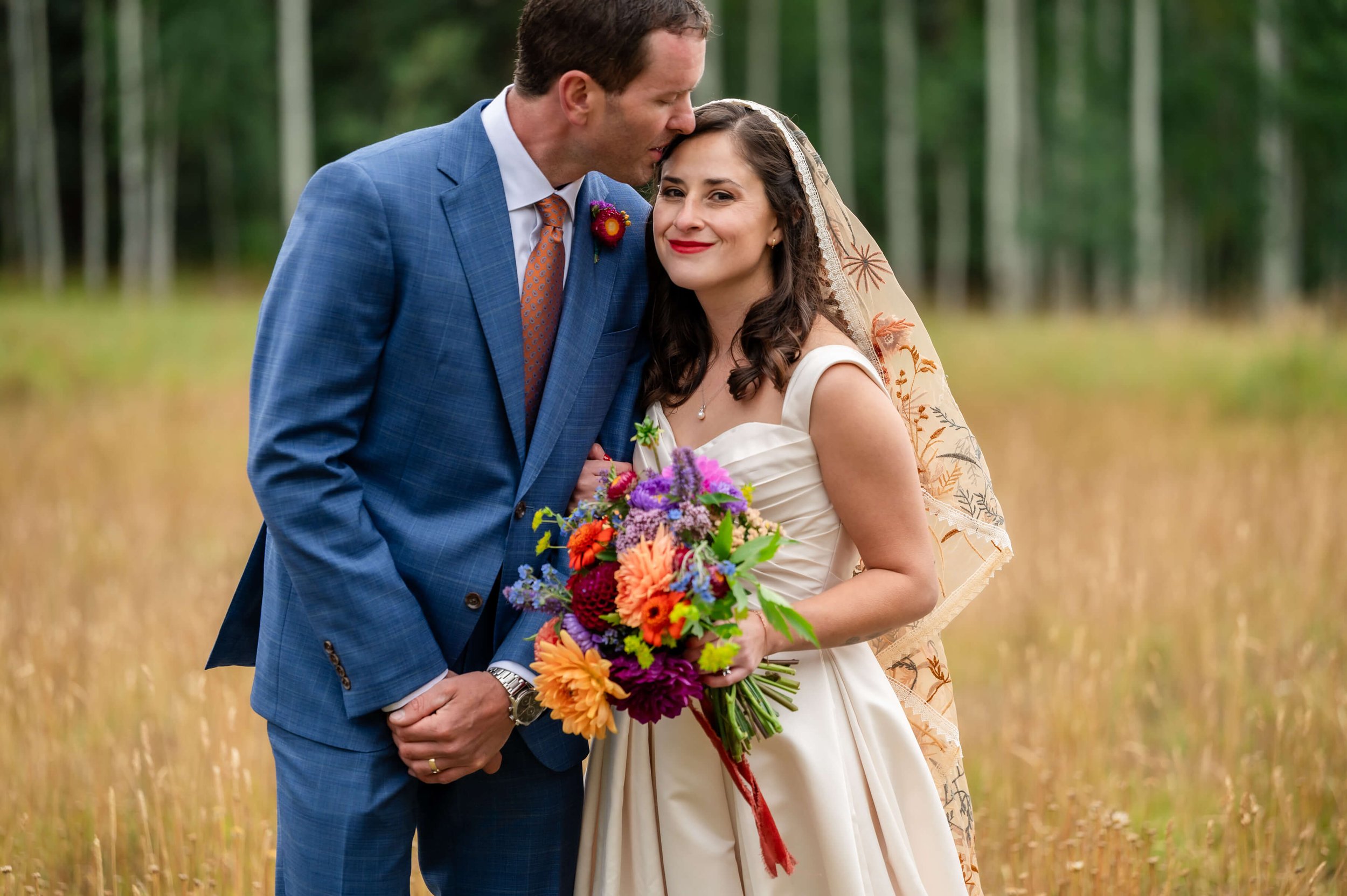 Bride and groom laughing together in light rain, surrounded by evergreens and soft mountain fog at The Benchmark in Durango, Colorado.