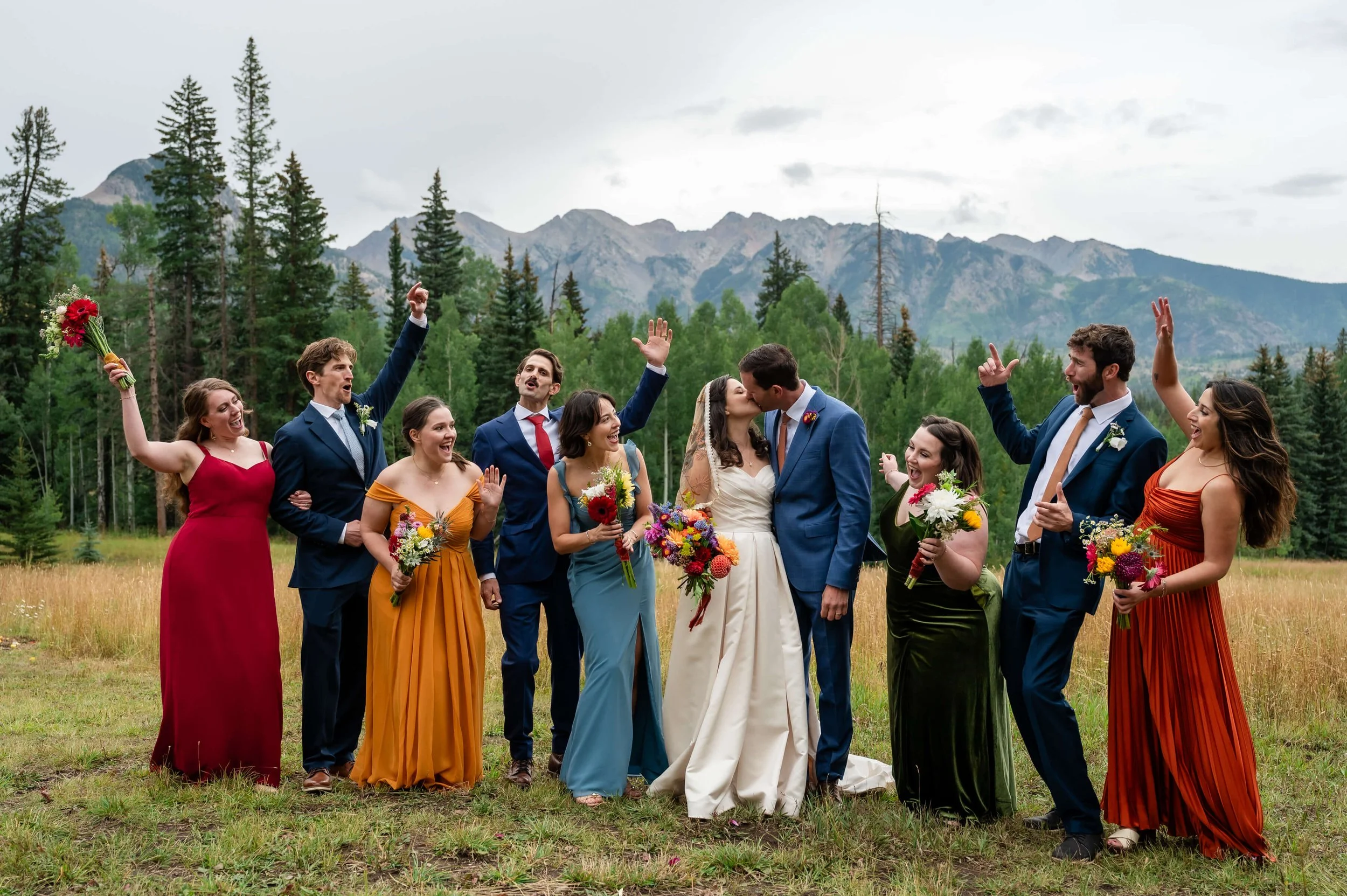Bridesmaids in bold, bright dresses standing with the bride in the North Meadow at The Benchmark, with misty mountains and soft rain in the background.