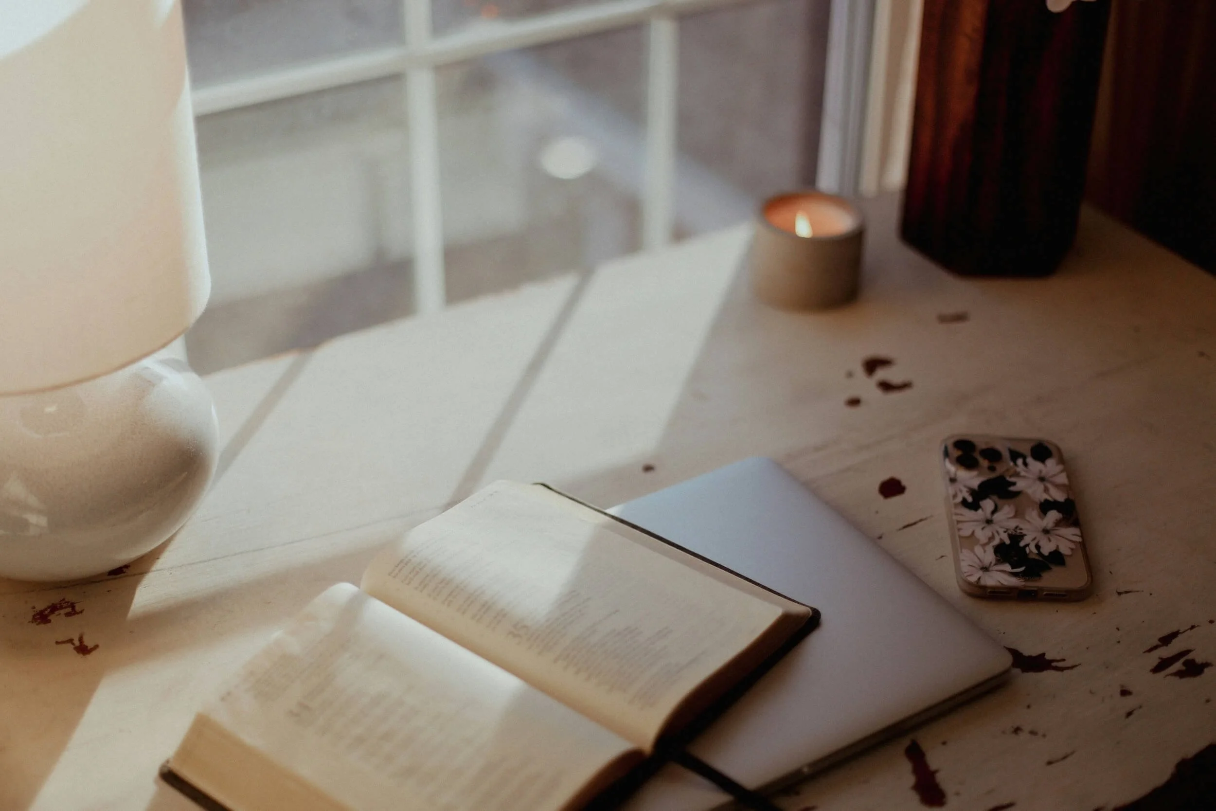 Open journal with a pen and candle on a table, representing reflection and online pet loss support for those navigating grief.
