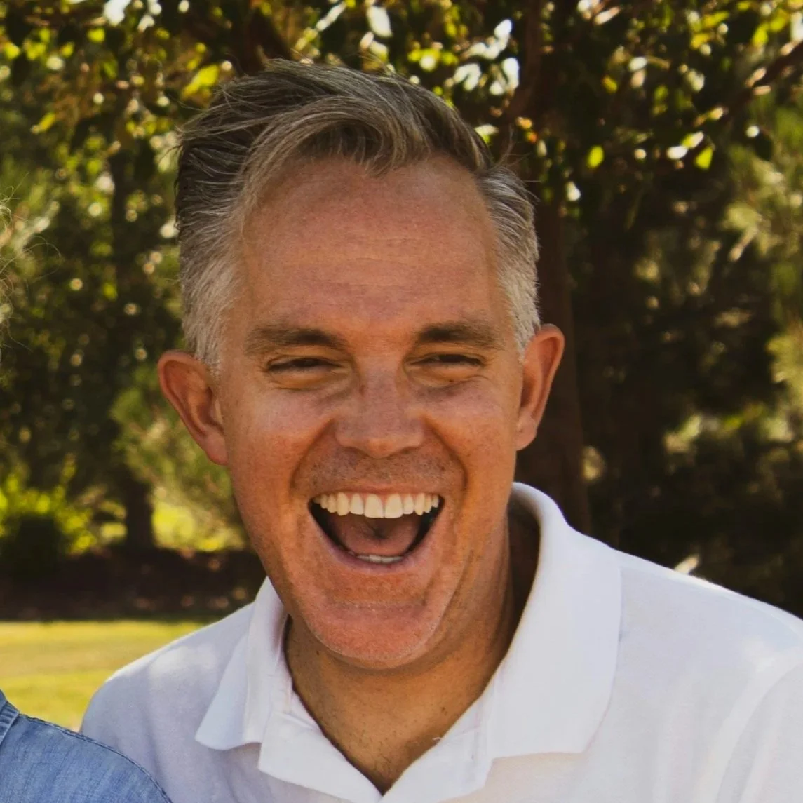 Smiling man outdoors with trees in background