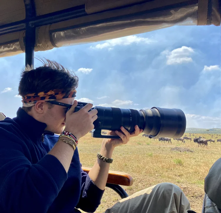 A person photographing with a long lens from an open vehicle.