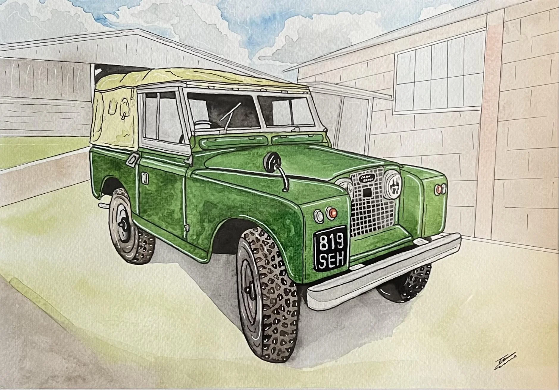 A green vintage Land Rover Defender with a beige soft top, parked in a driveway between two wooden garages, under a partly cloudy sky.