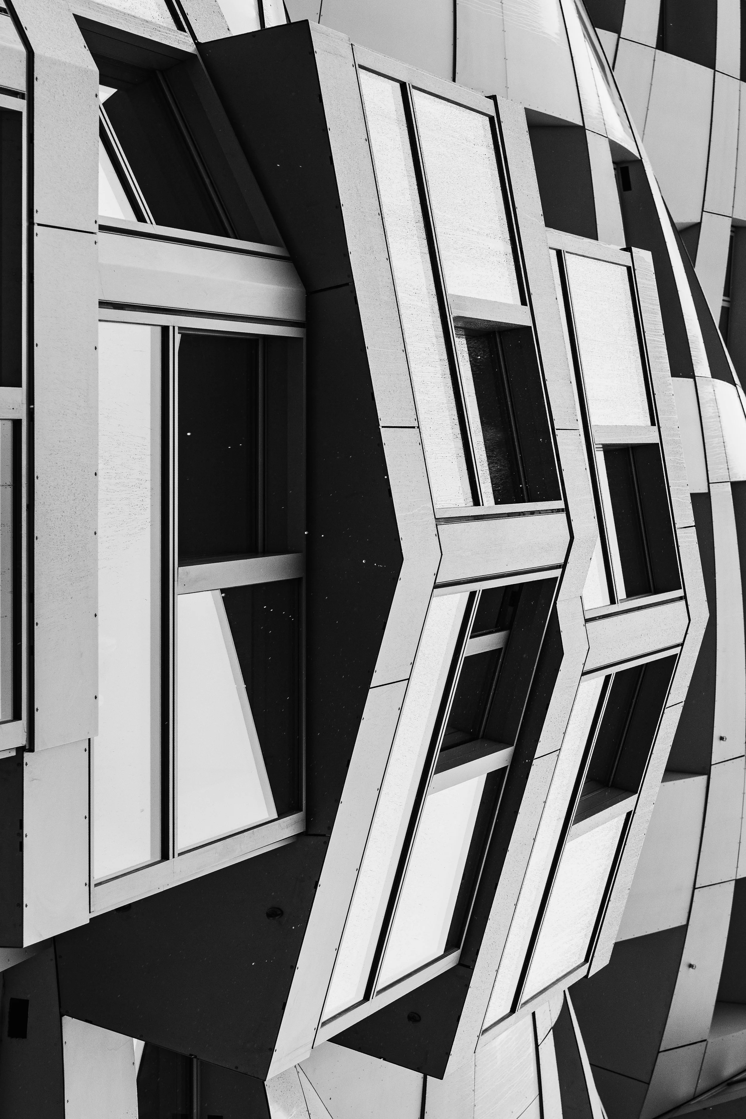 Close-up of a modern building's facade with geometric windows and panels in black and white.