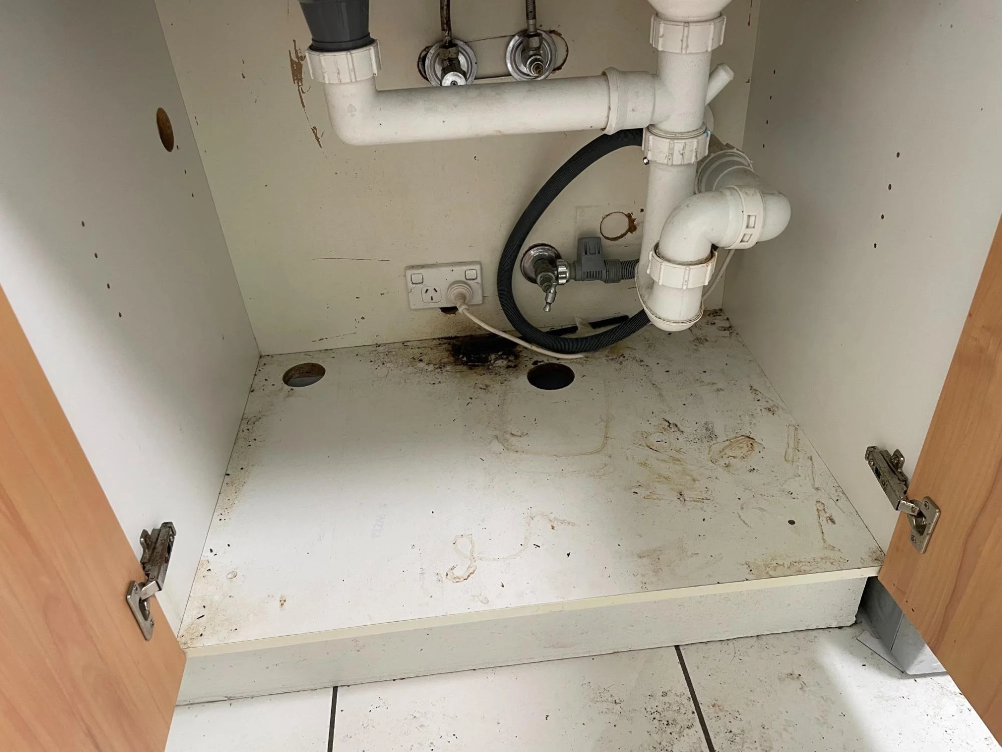 Cupboards under laundry sink before deep cleaning by Kat Clean Sydney, NSW