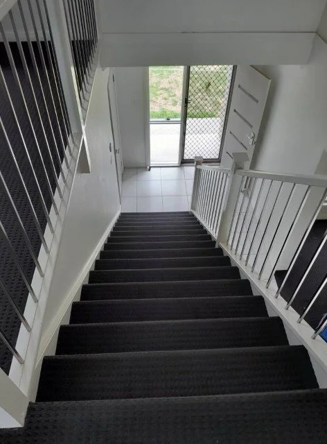 Flight of carpeted stairs leading down to a white tiled landing.