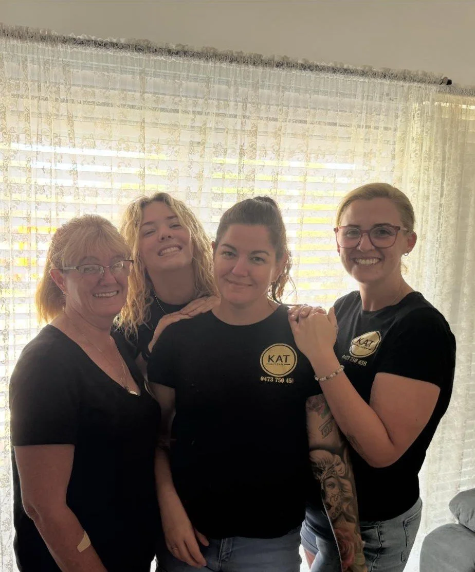 Four women in black t-shirts standing in a group.