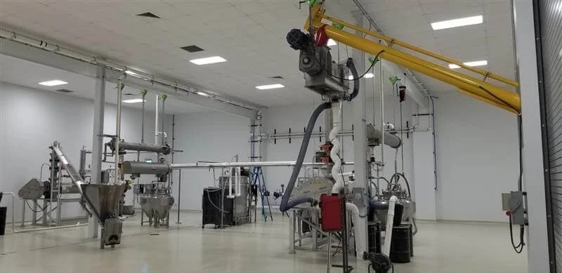 Modern pharmaceutical manufacturing facility with stainless steel processing equipment, overhead crane system, and cleanroom environment