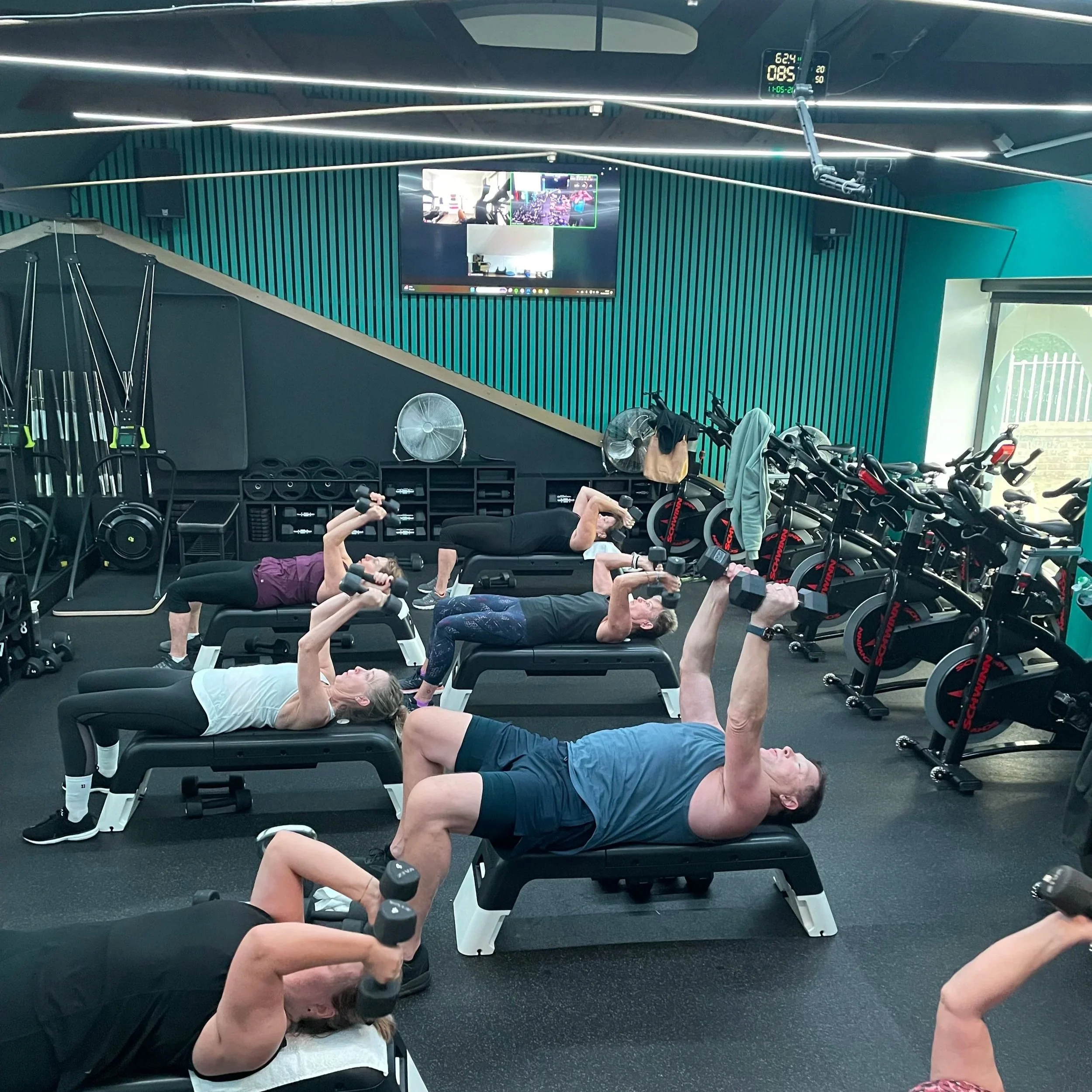 Small group fitness session with members doing tricep extensions