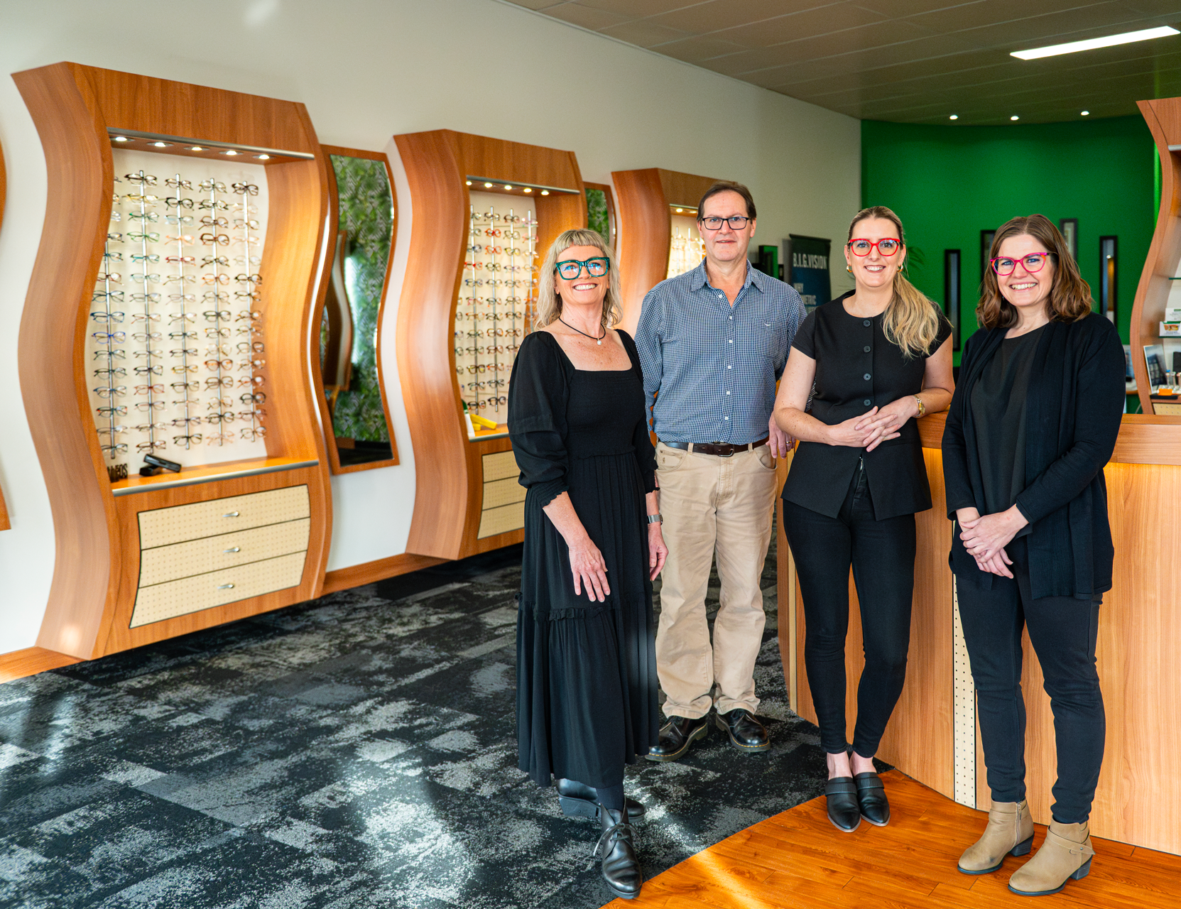 The Focus Optical Albany team standing inside the eyewear store, with display racks of glasses behind them.
