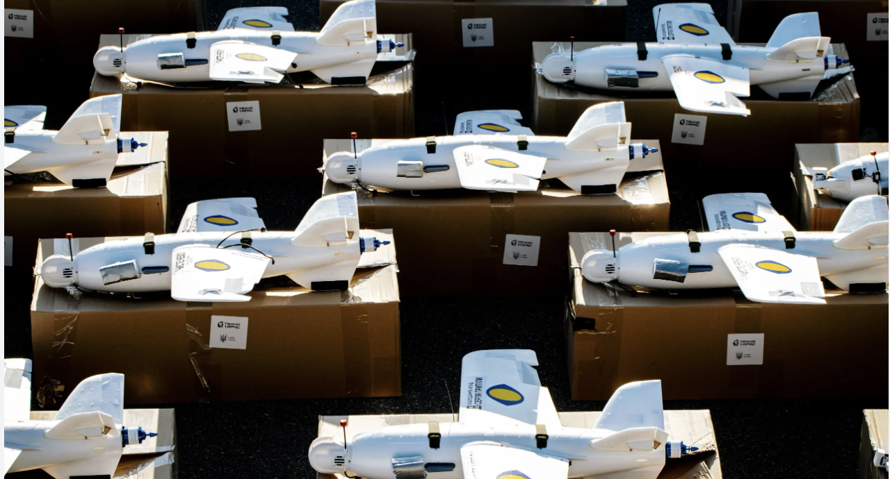 Multiple model rockets with white bodies and wings, each featuring a blue and yellow logo, resting on top of brown cardboard boxes.