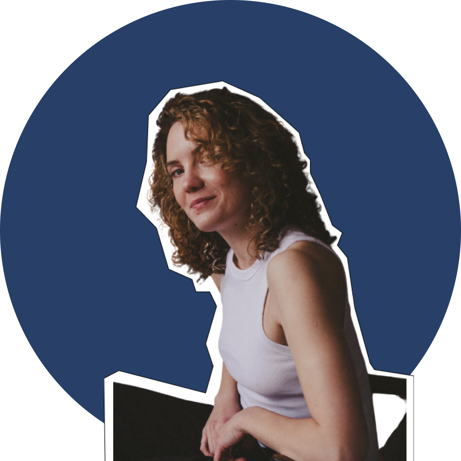 A woman with curly red hair wearing a white sleeveless shirt, sitting on a dark chair against a dark blue background, looking at the camera with a slight smile.