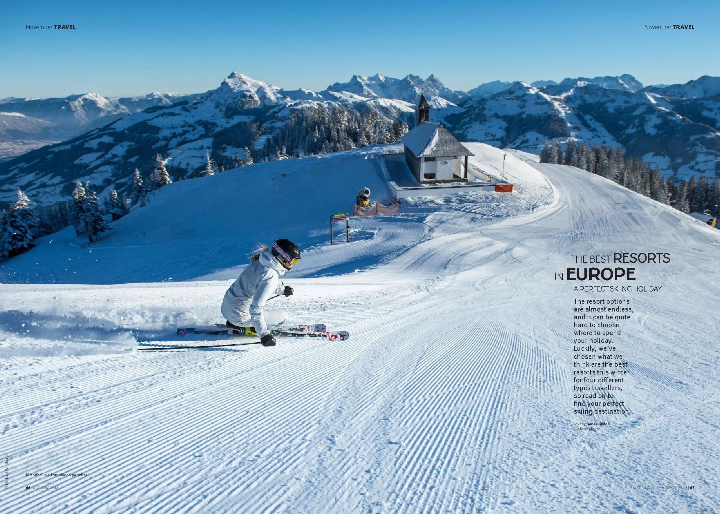 A person skiing down a snowy slope near a small house with mountains in the background, under a clear blue sky.