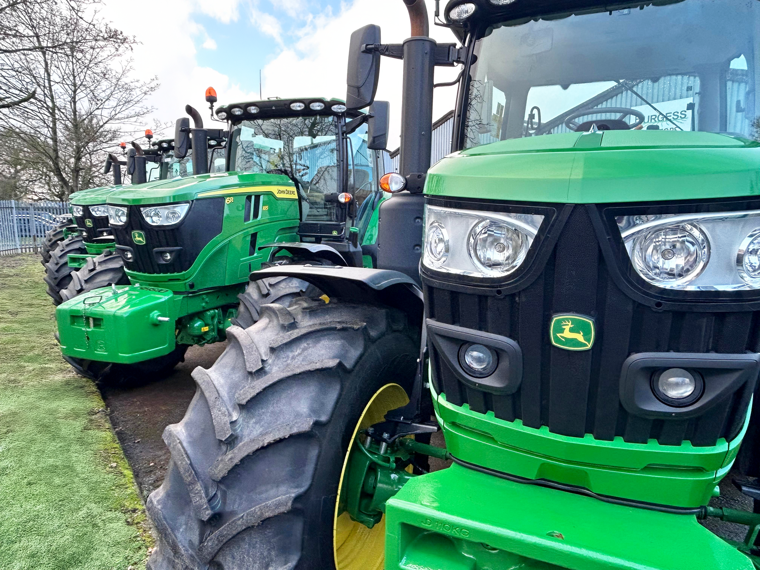 A row of green John Deere tractors parked outdoors