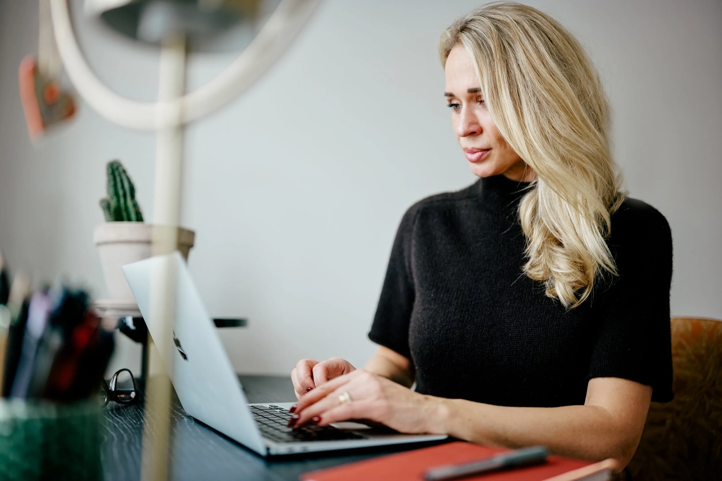 Kvindelig person med blond hår arbejder på en bærbar computer i et hjemmekontor.
