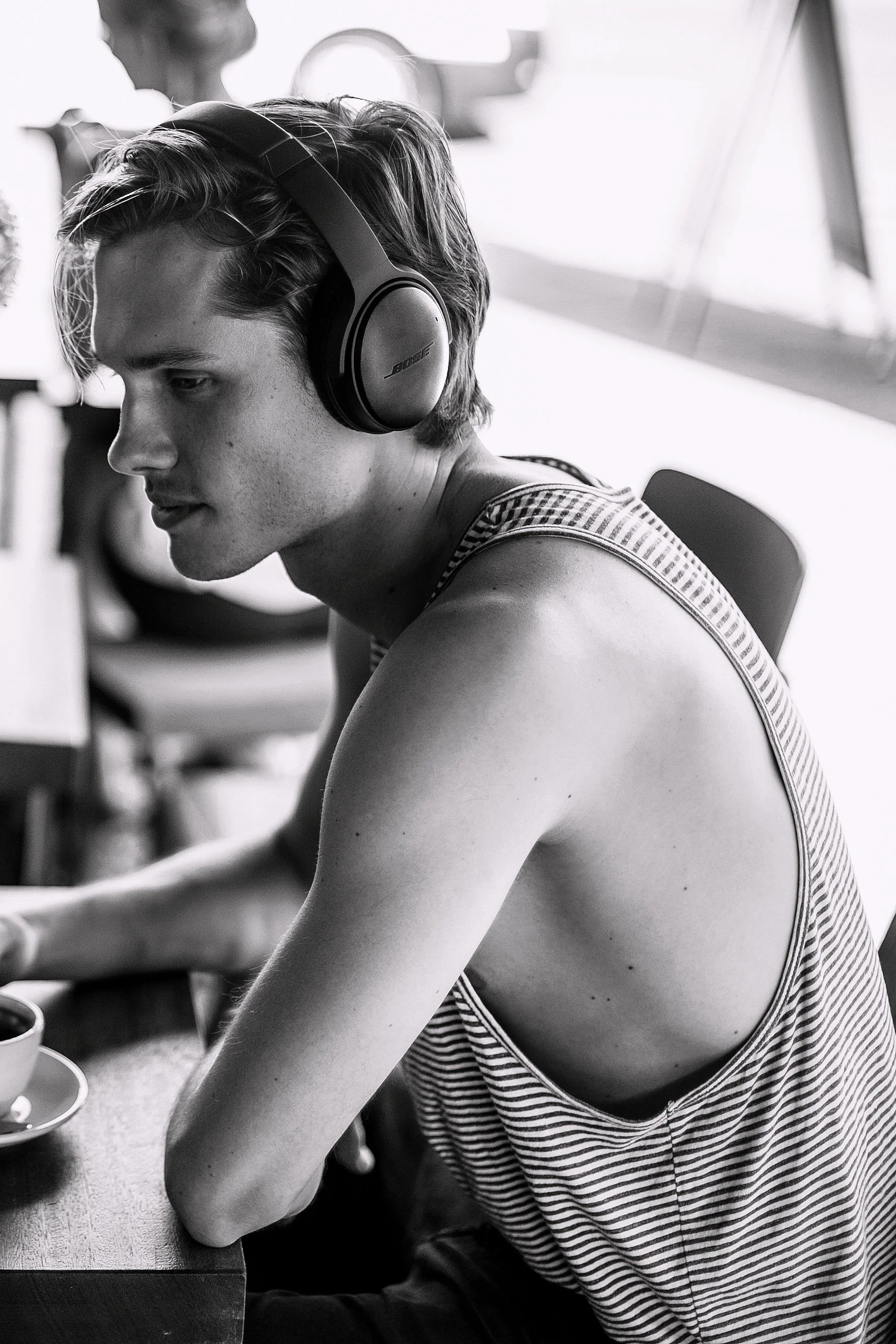 A young man wearing headphones sitting at a table, focused on something in front of him.