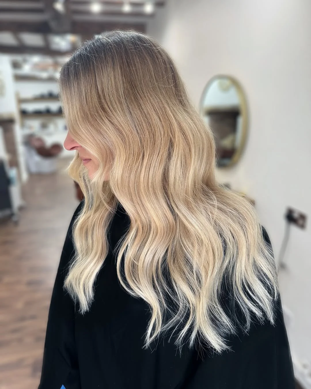 Side view of a woman with long, wavy blonde hair in a salon.