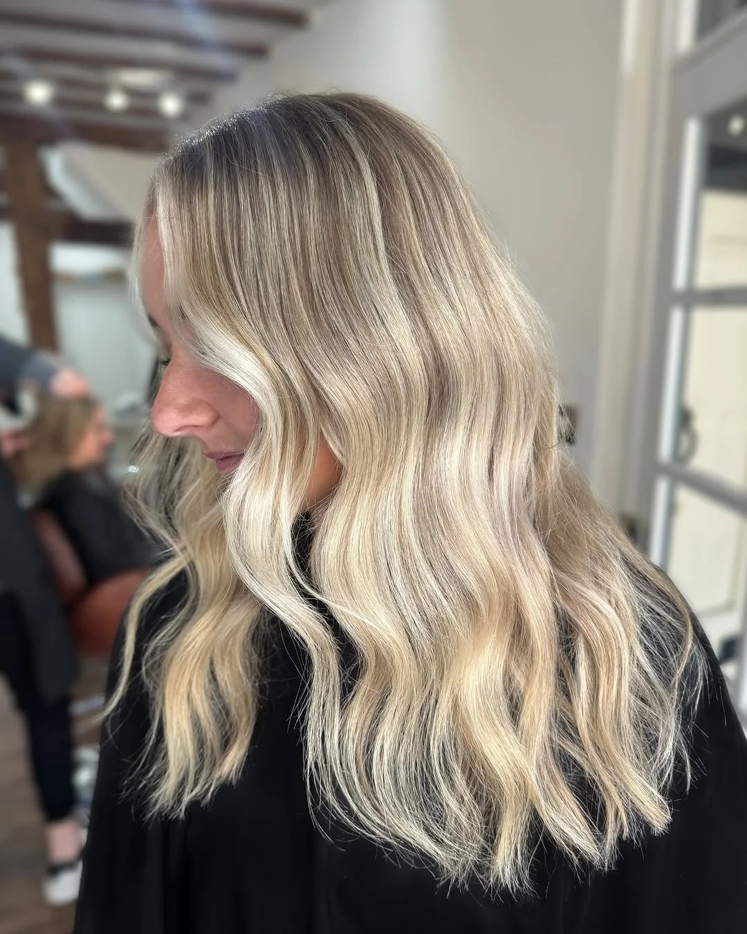 Woman with long, wavy blonde hair in a salon.