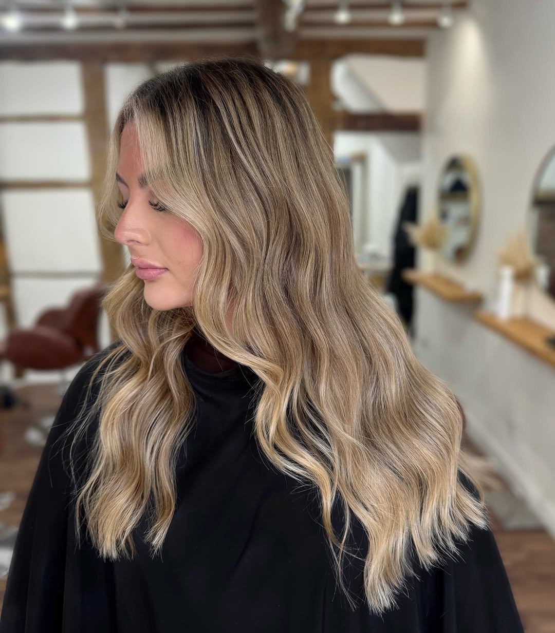 A woman with wavy, blonde hair in a modern salon setting.