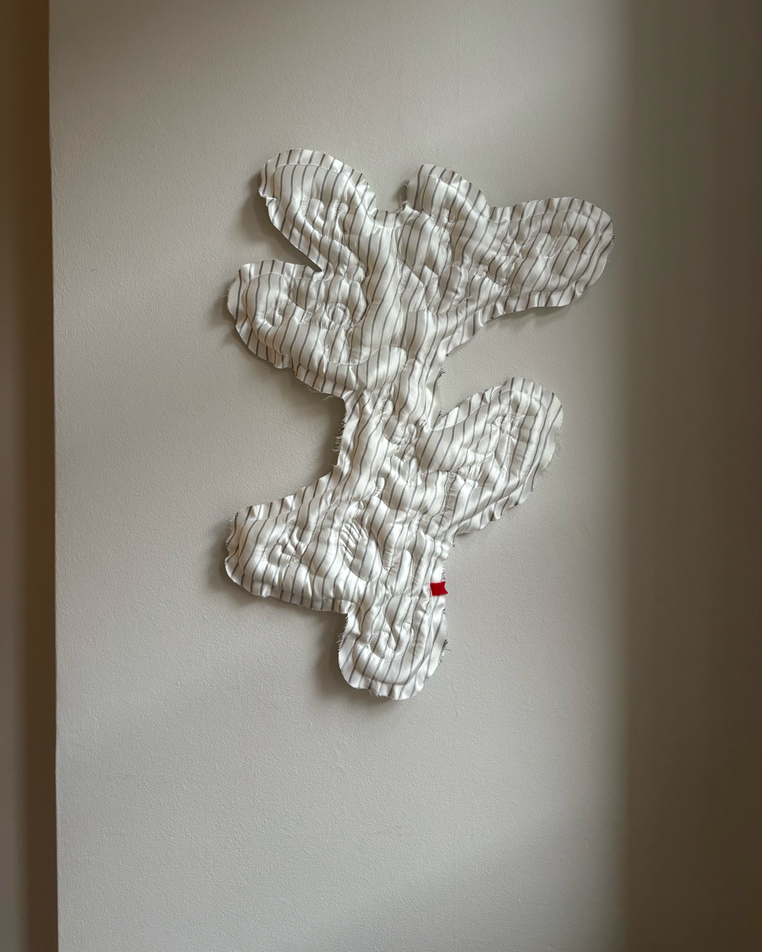 Studio Ateme white and grey striped quilted artwork with stitched symbols and a raw frilly edge.