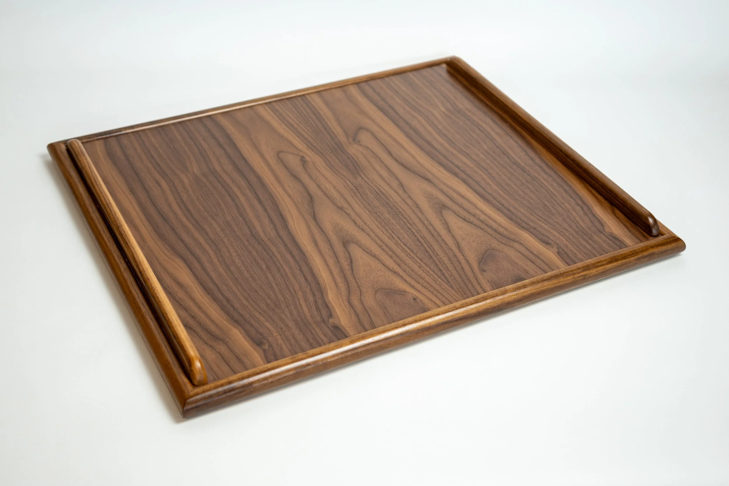 A rectangular wooden tray with raised edges placed on a white surface.
