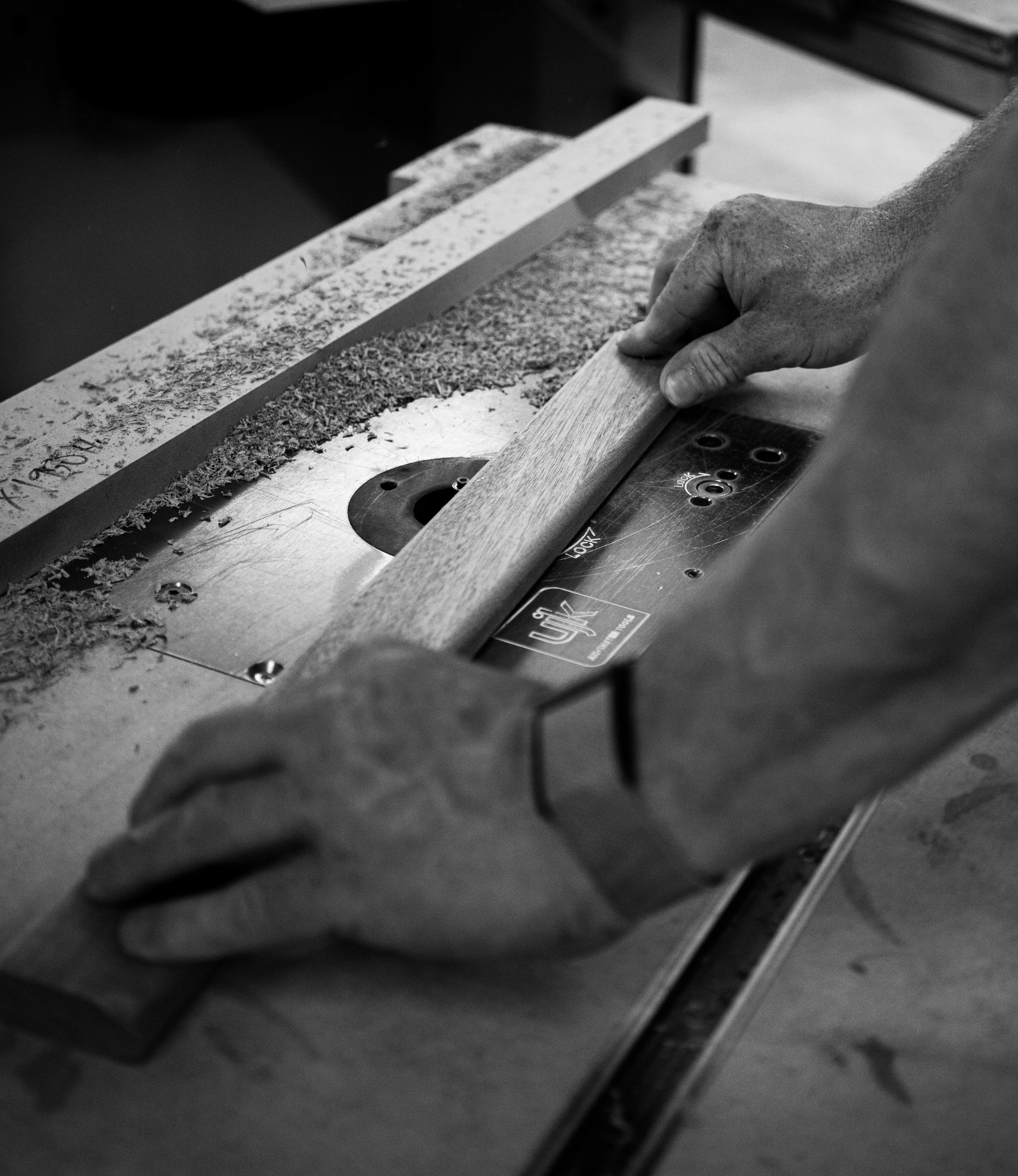 A person filing a piece of wood with a power planer machine in a workshop.