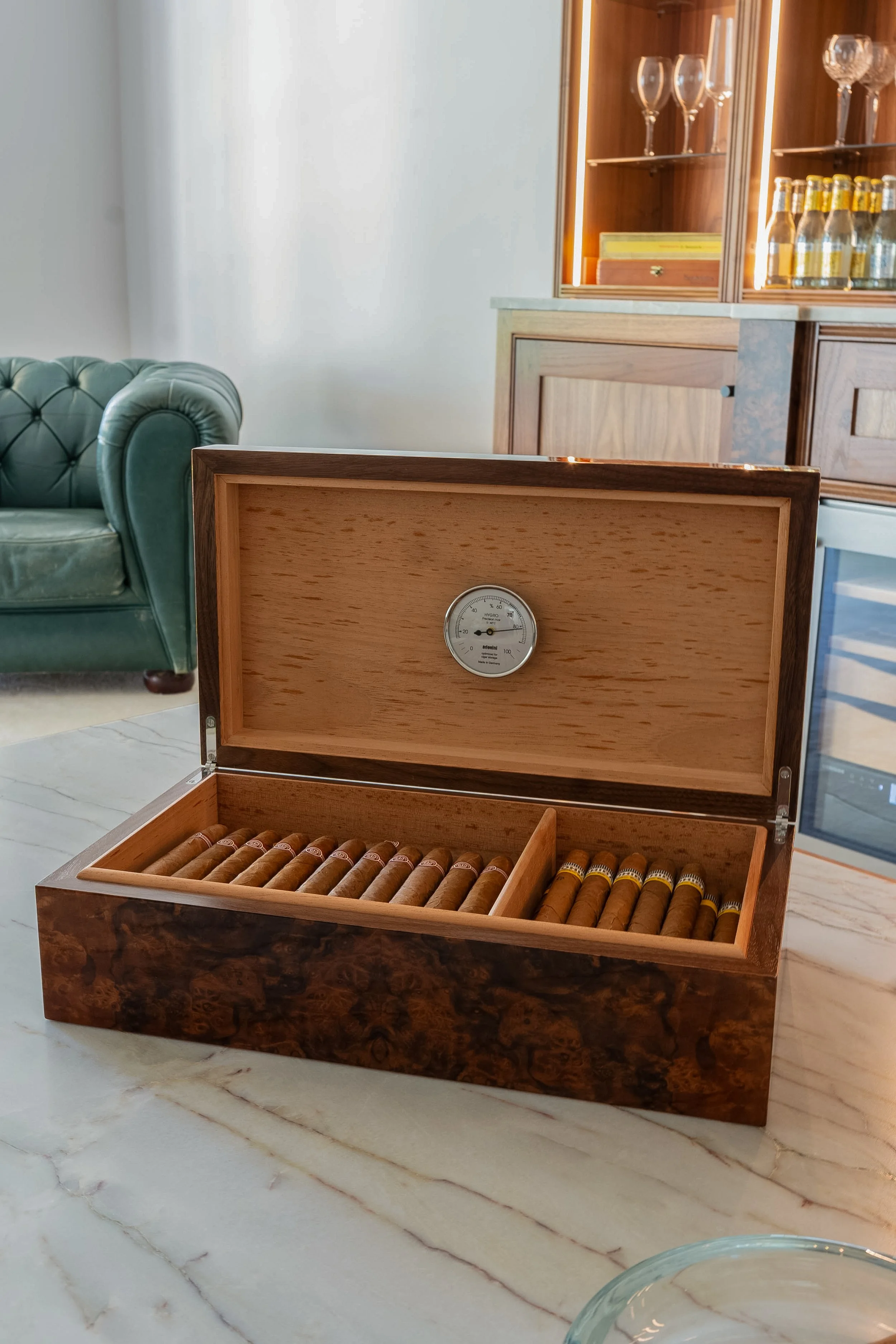 Open wooden cigar humidor with cigars inside, on a marble surface.