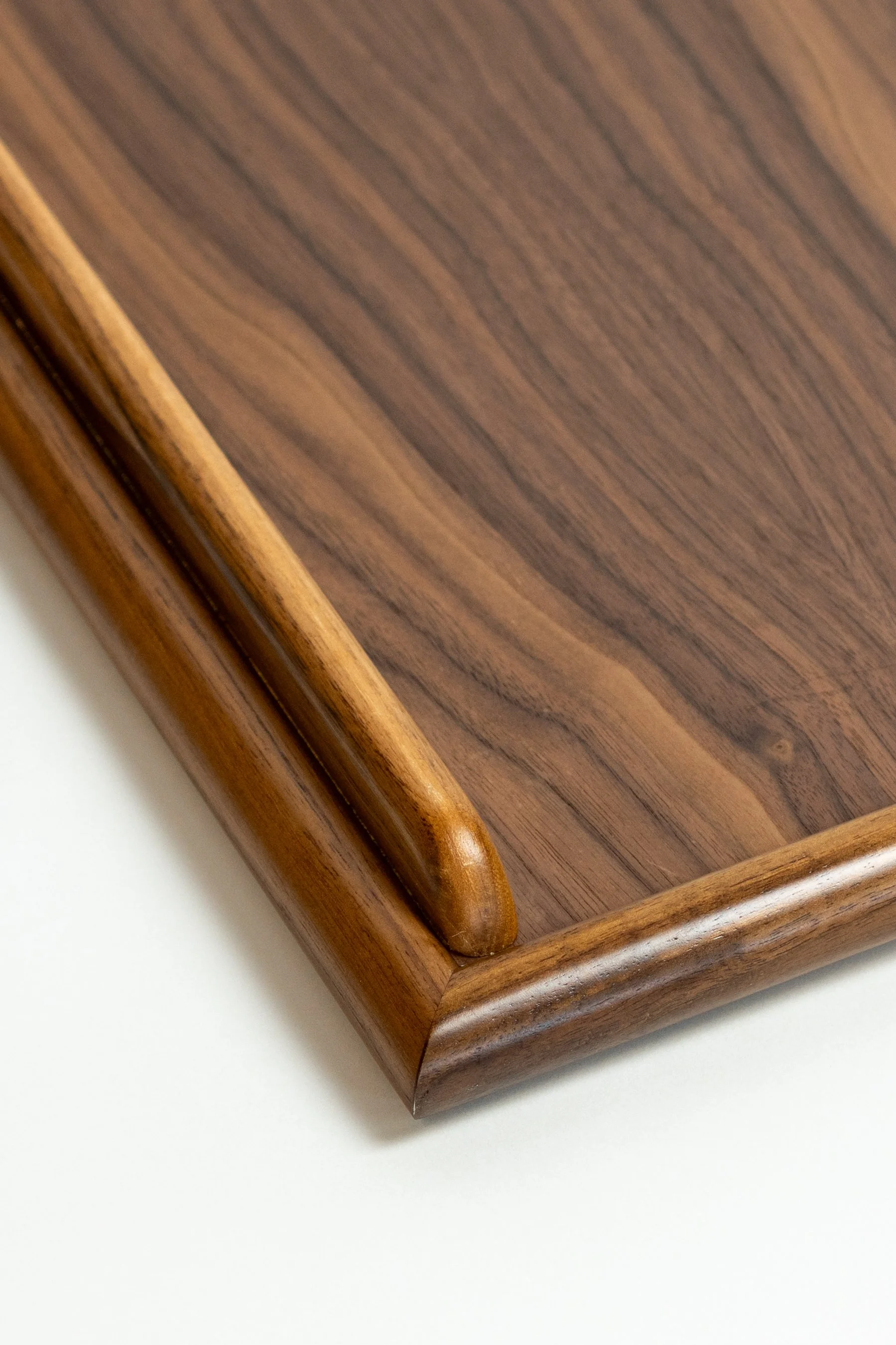 Close-up of a wooden table with a dark stain finish and rounded edge.