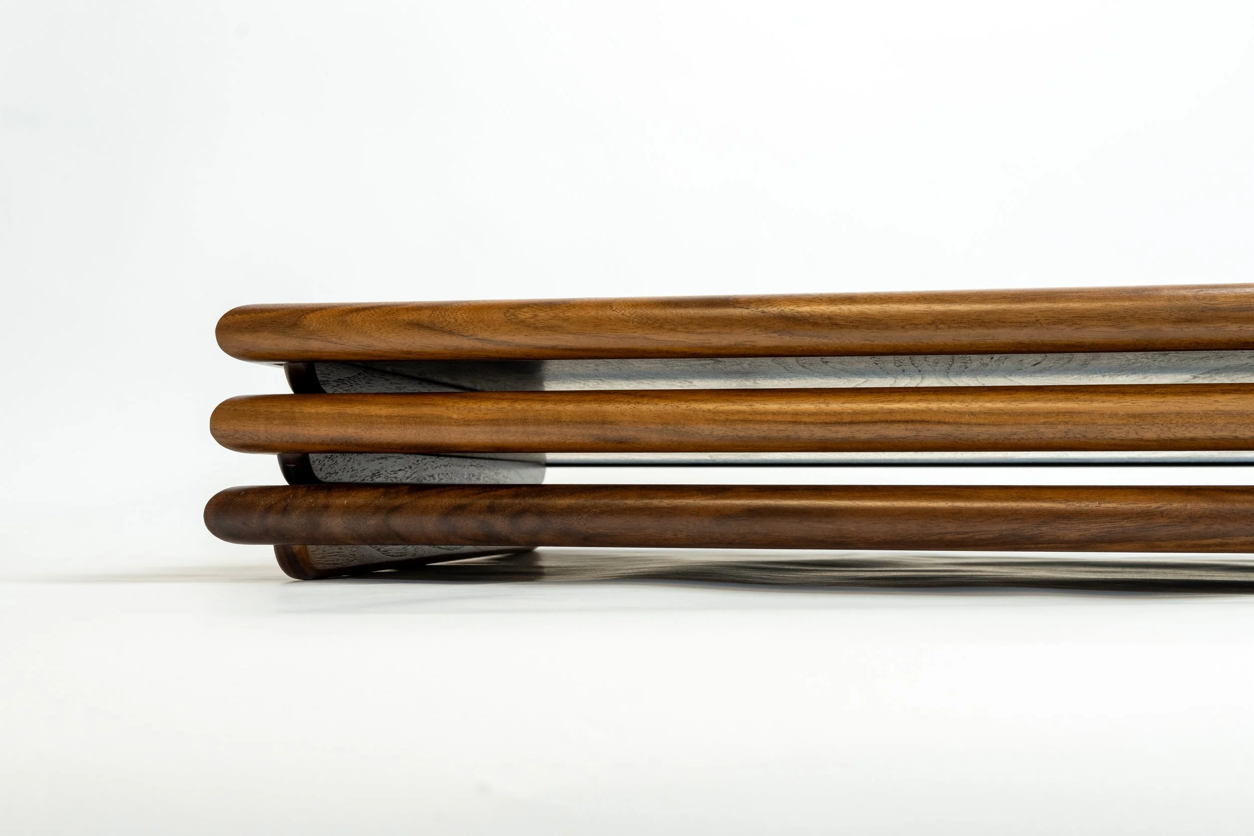 Close-up of a stack of wooden chair arms against a white background.
