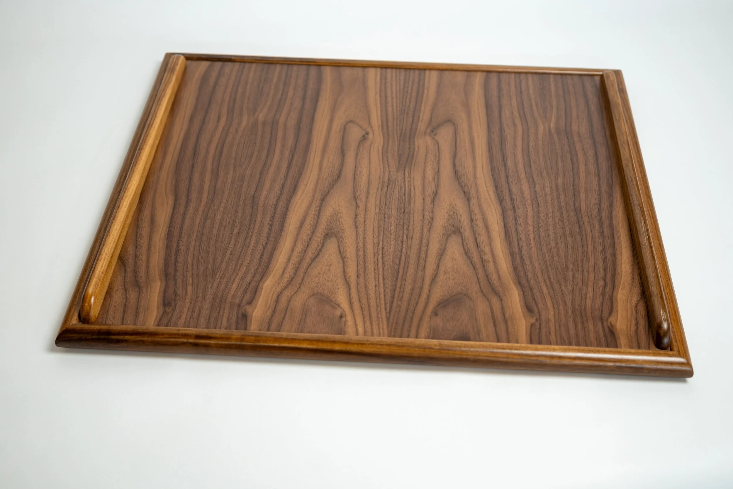 A wooden tray with raised edges on a white surface.
