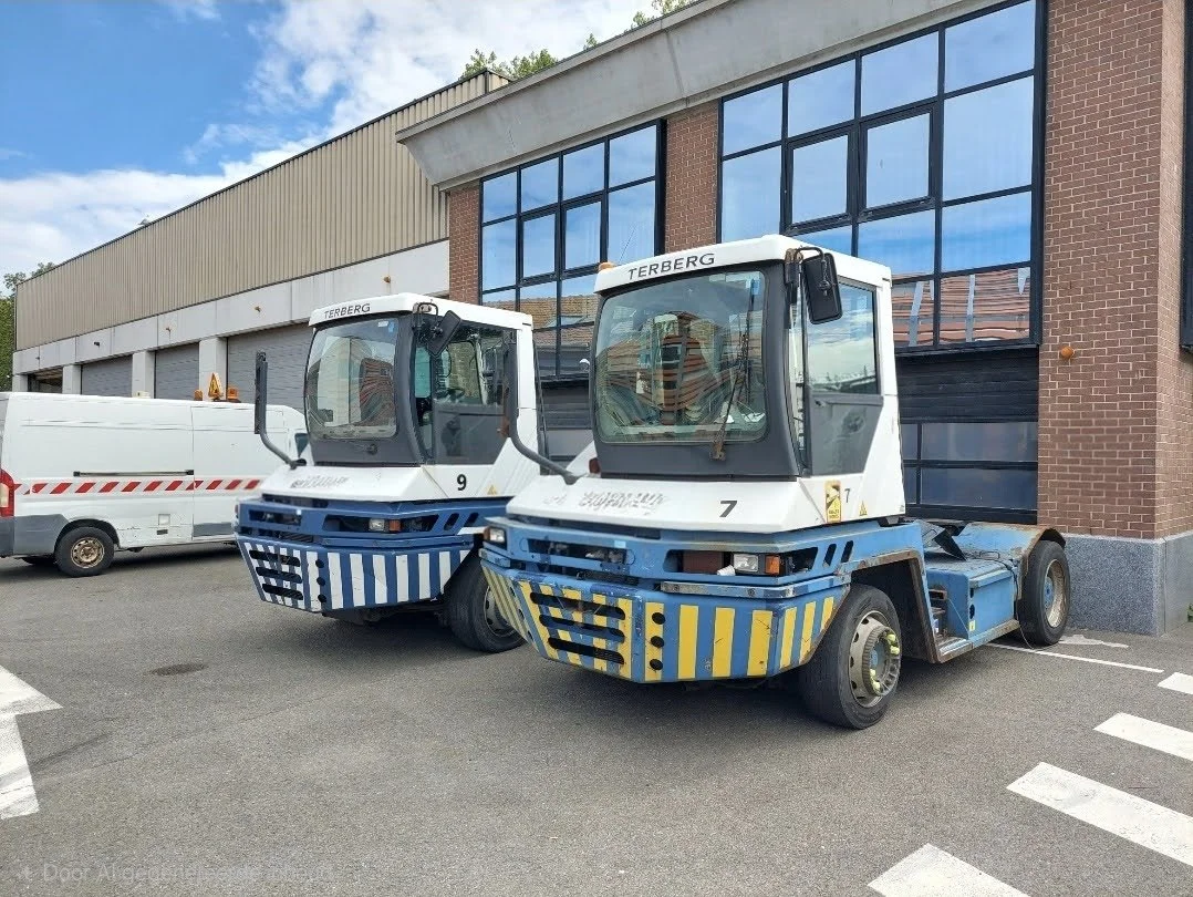 Twee verkeersongevallenvoertuigen geparkeerd voor een gebouw, met een witte bestelwagen op de achtergrond.