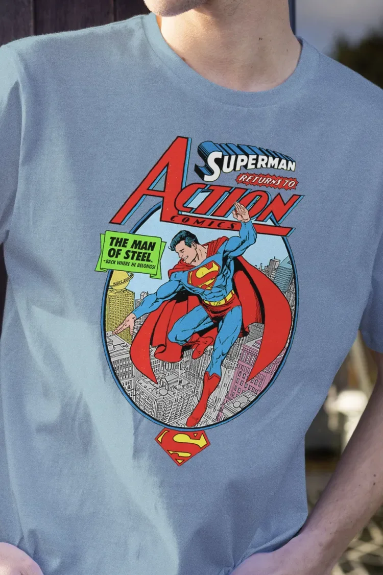 Person wearing a light blue T-shirt featuring a Superman Action Comics comic book cover design with Superman flying over a city.