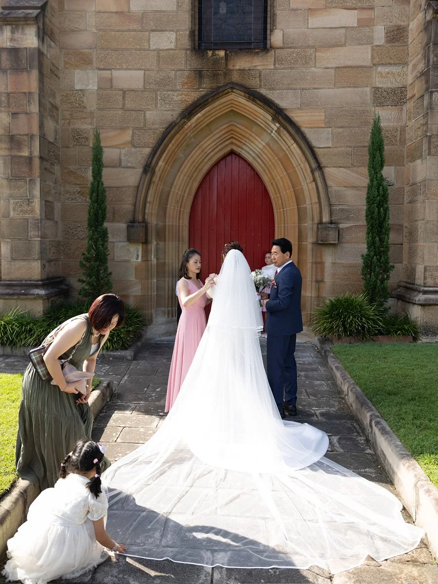 Bridesmaids arranging the veil outside the Garrison Church red door, Millers Point