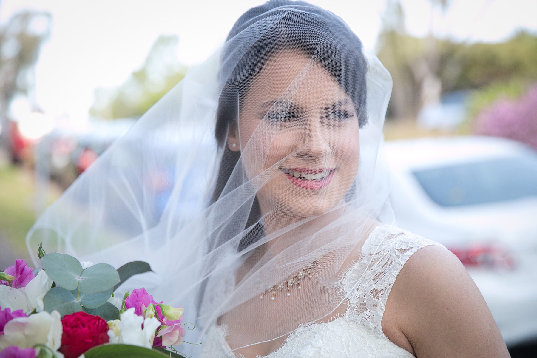 Close portrait of the bride smiling in her veil outside St Andrews Anglican Church Roseville