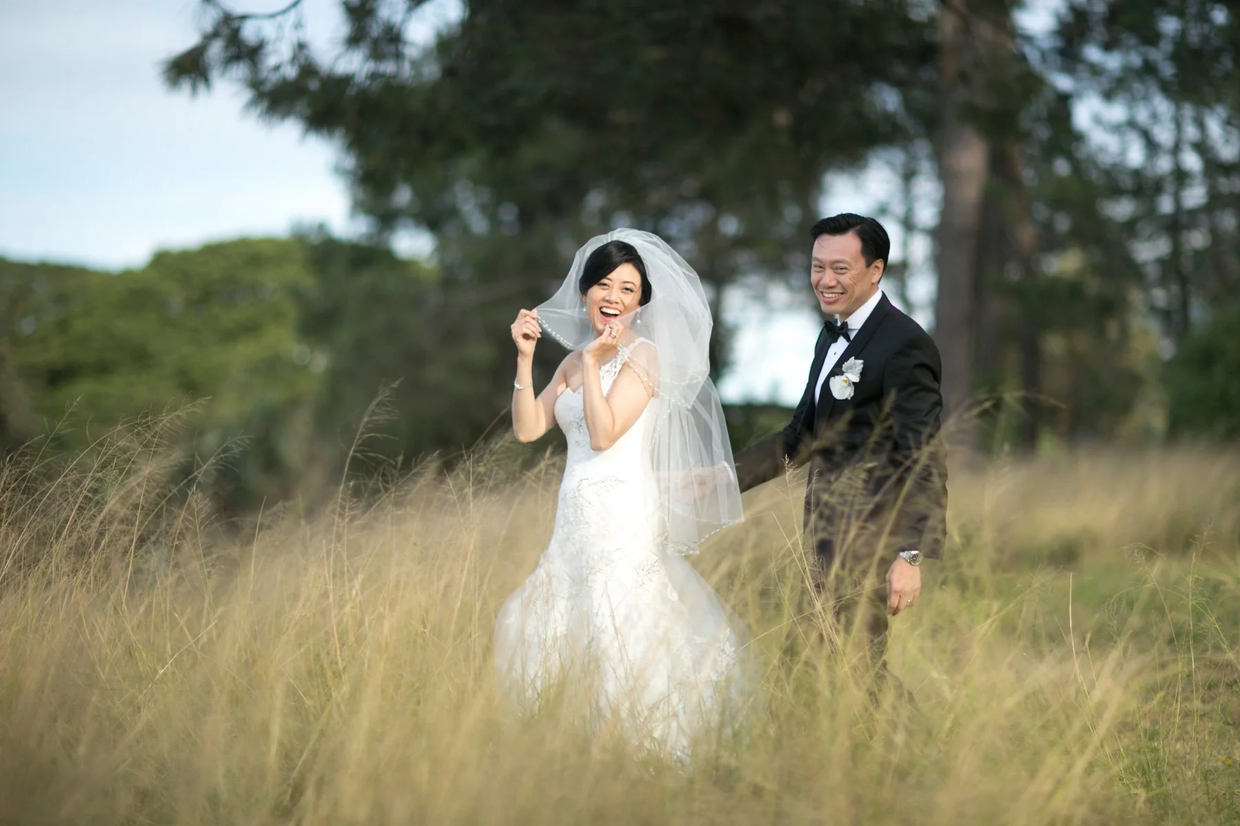 Bride playing with veil in long grass, Centennial Park Sydney