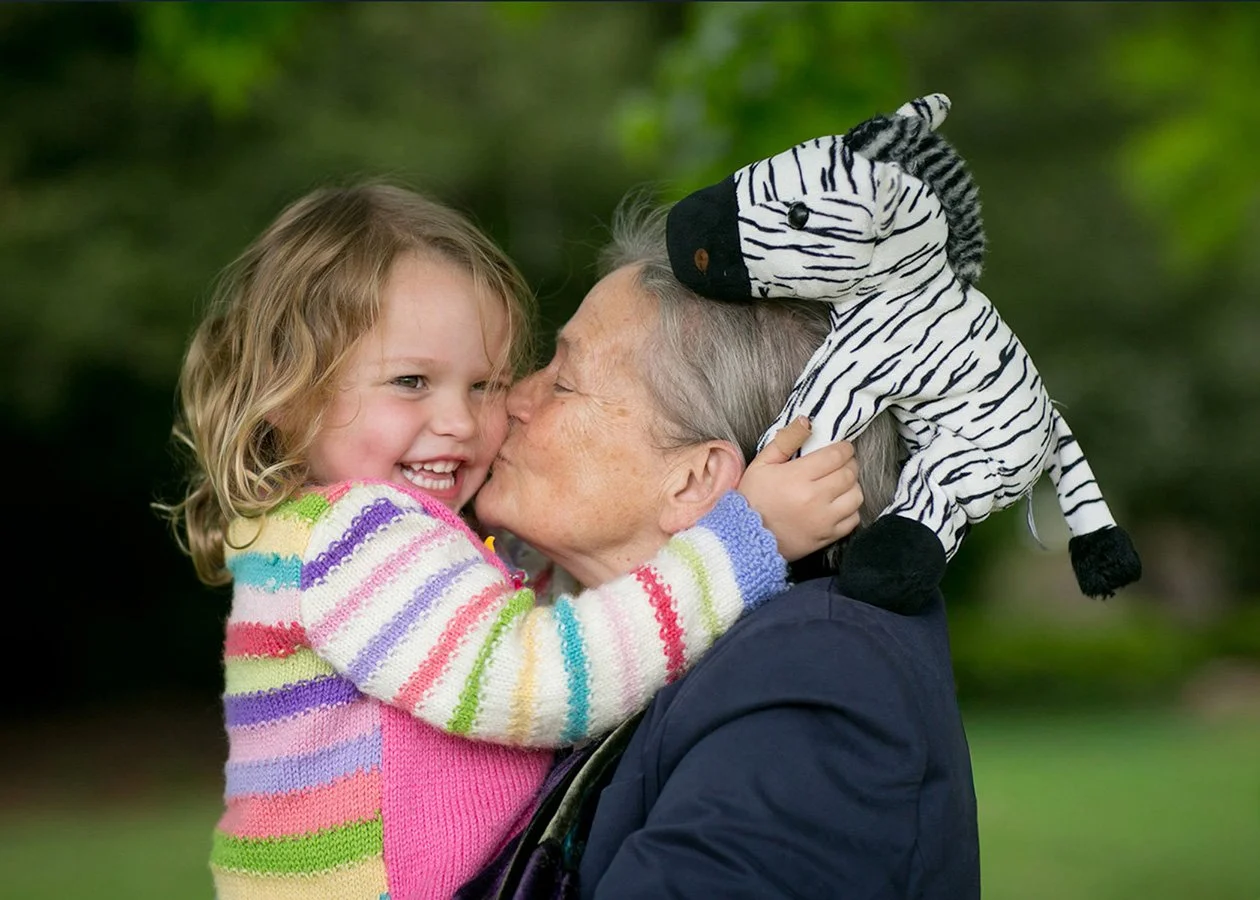 Grandmother kissing young granddaughter in park