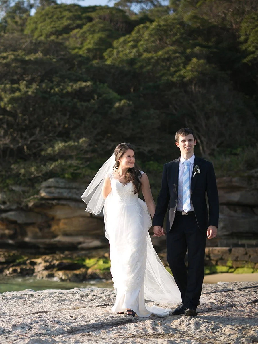 Bride and groom walking portrait on the stone pier at Bradleys Head Mosman