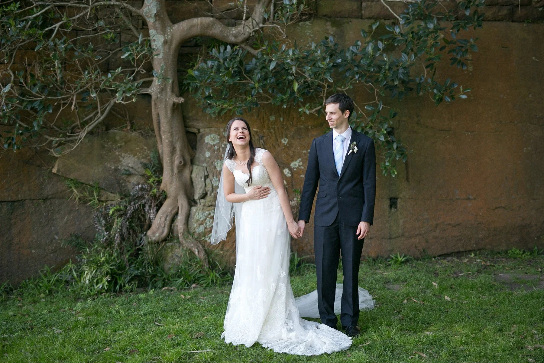 Bride and groom laughing together beneath the Moreton Bay fig tree at Bradleys Head Mosman