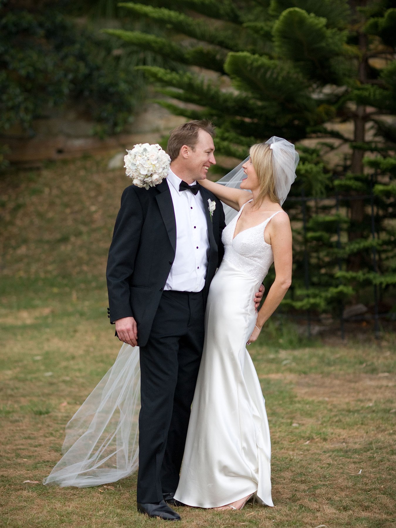 Bride and groom sharing a candid laugh beneath a tree at the Royal Botanic Gardens Sydney
