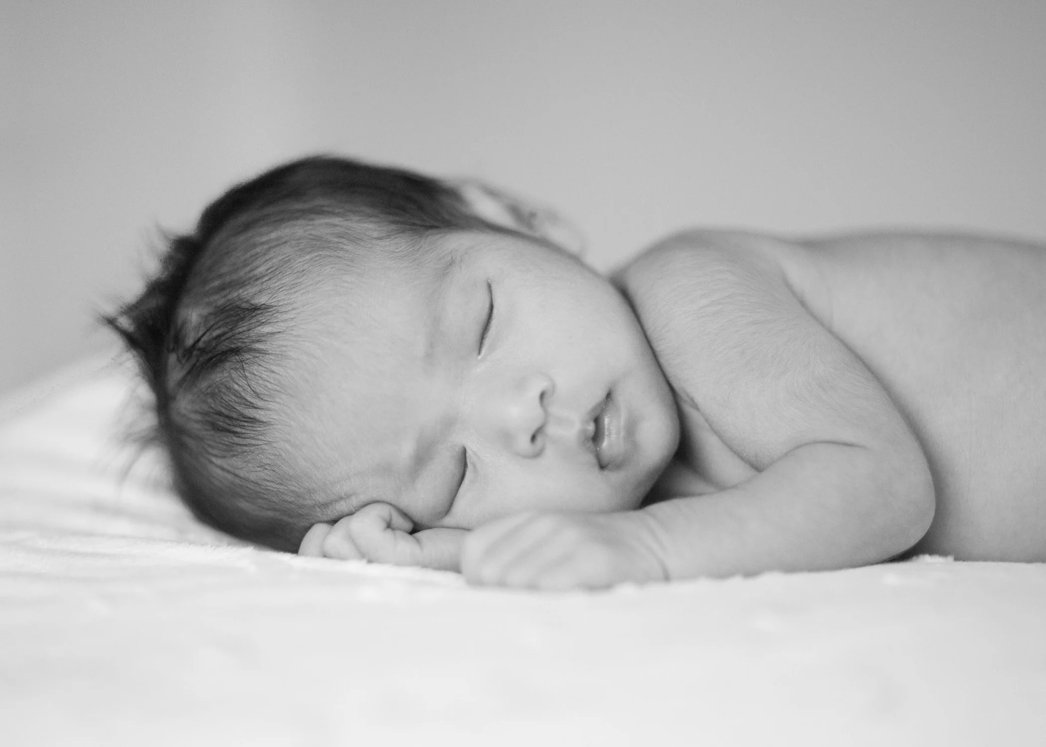 Sleeping newborn baby lying on white blanket