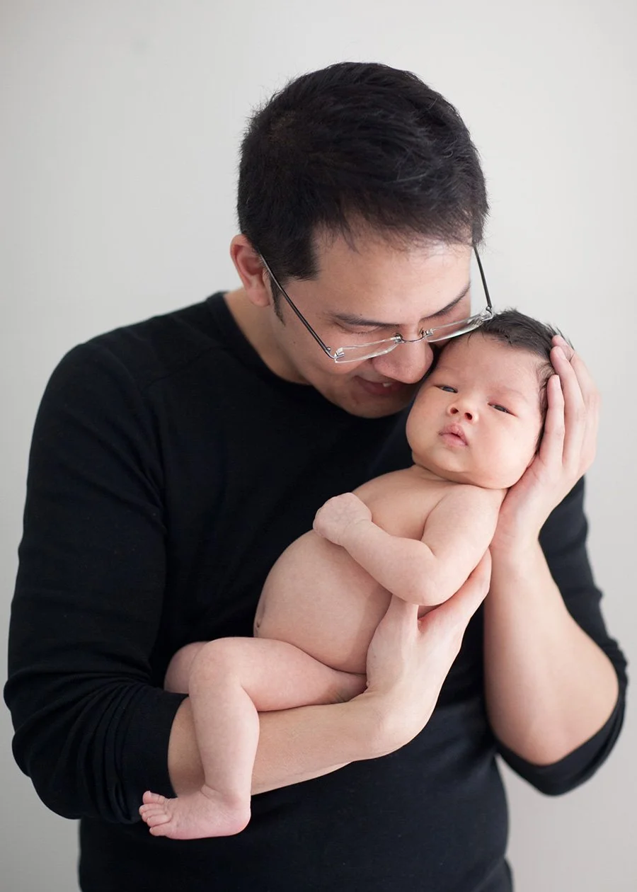 Father holding newborn baby against chest