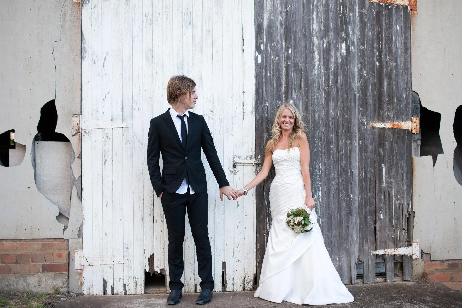 Couple hand in hand against wooden warehouse doors 