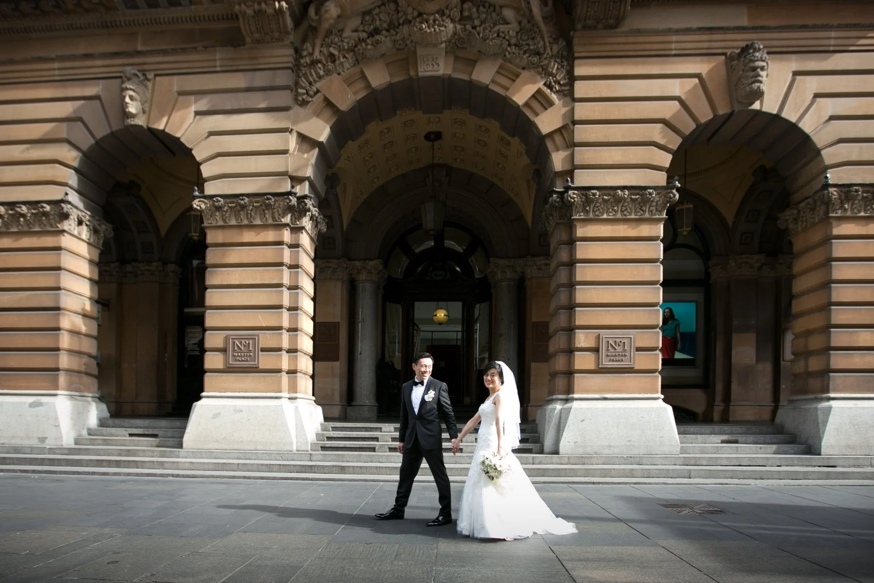 Bride and groom walking beneath GPO arches, Martin Place Sydney
