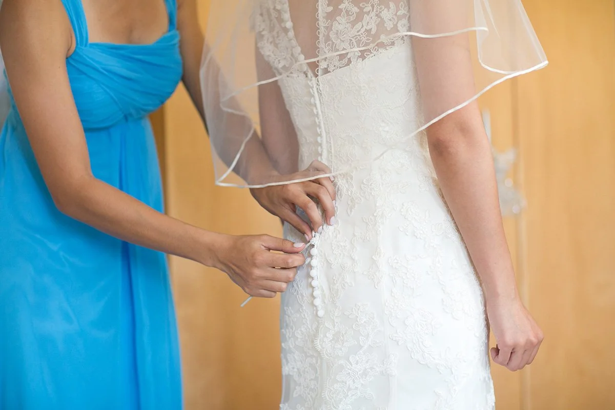 Bridesmaid fastening bride's wedding dress Sydney wedding preparation