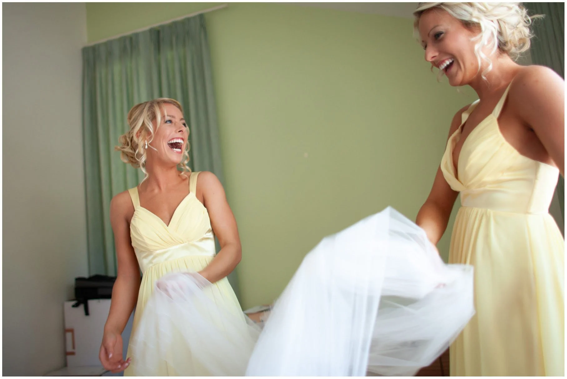 Bridesmaids laughing and playing with veil during bridal preparation