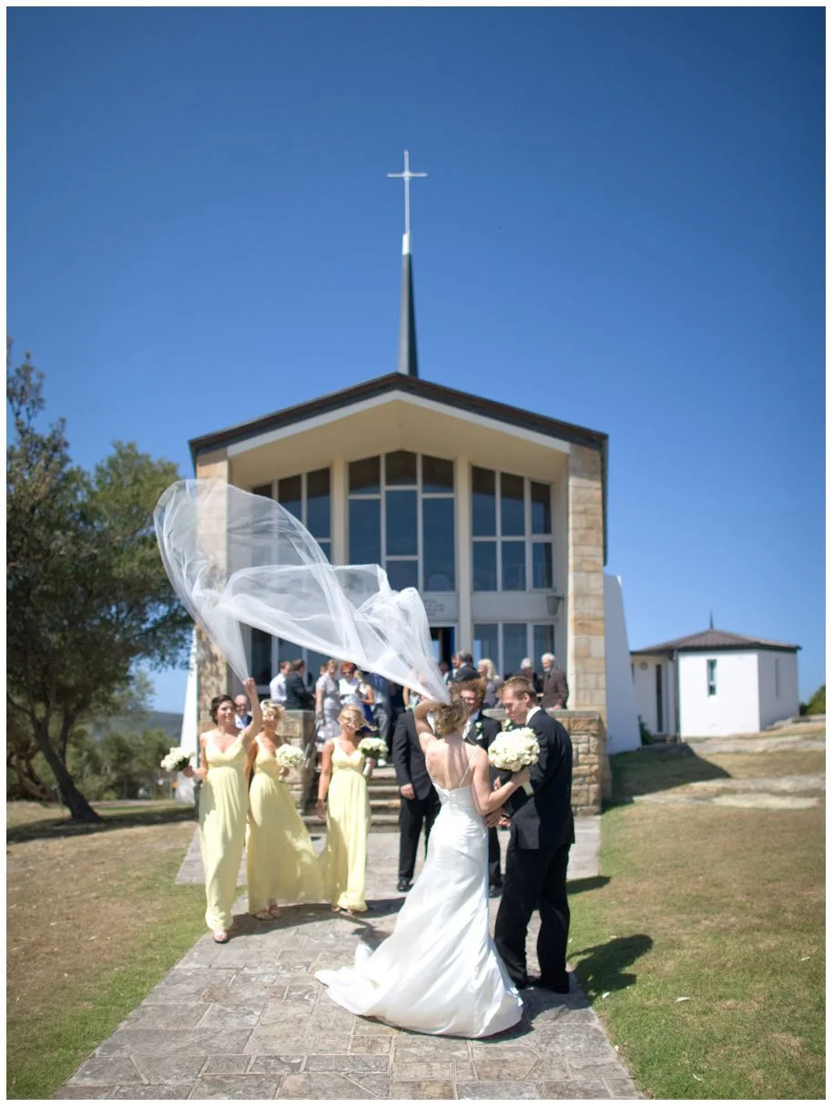 Bridal party with flying veil, outside HMAS Watson chapel, Watsons Bay