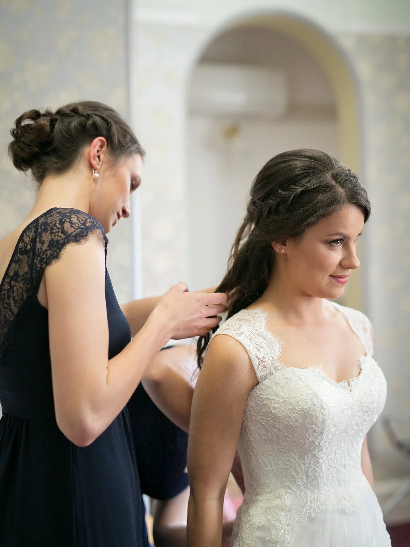 Bride having her dress fastened by her bridesmaid before the ceremony