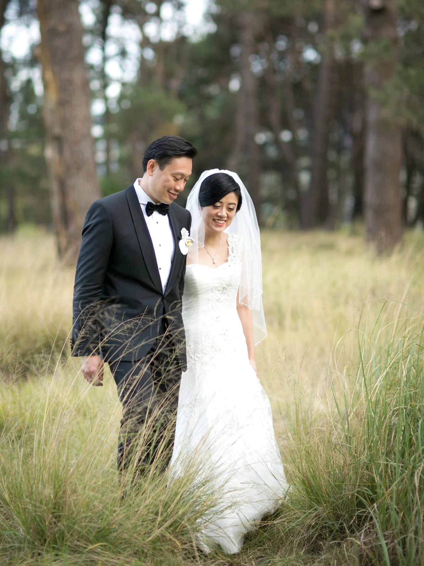 groom walking with bride through long grass centennial park