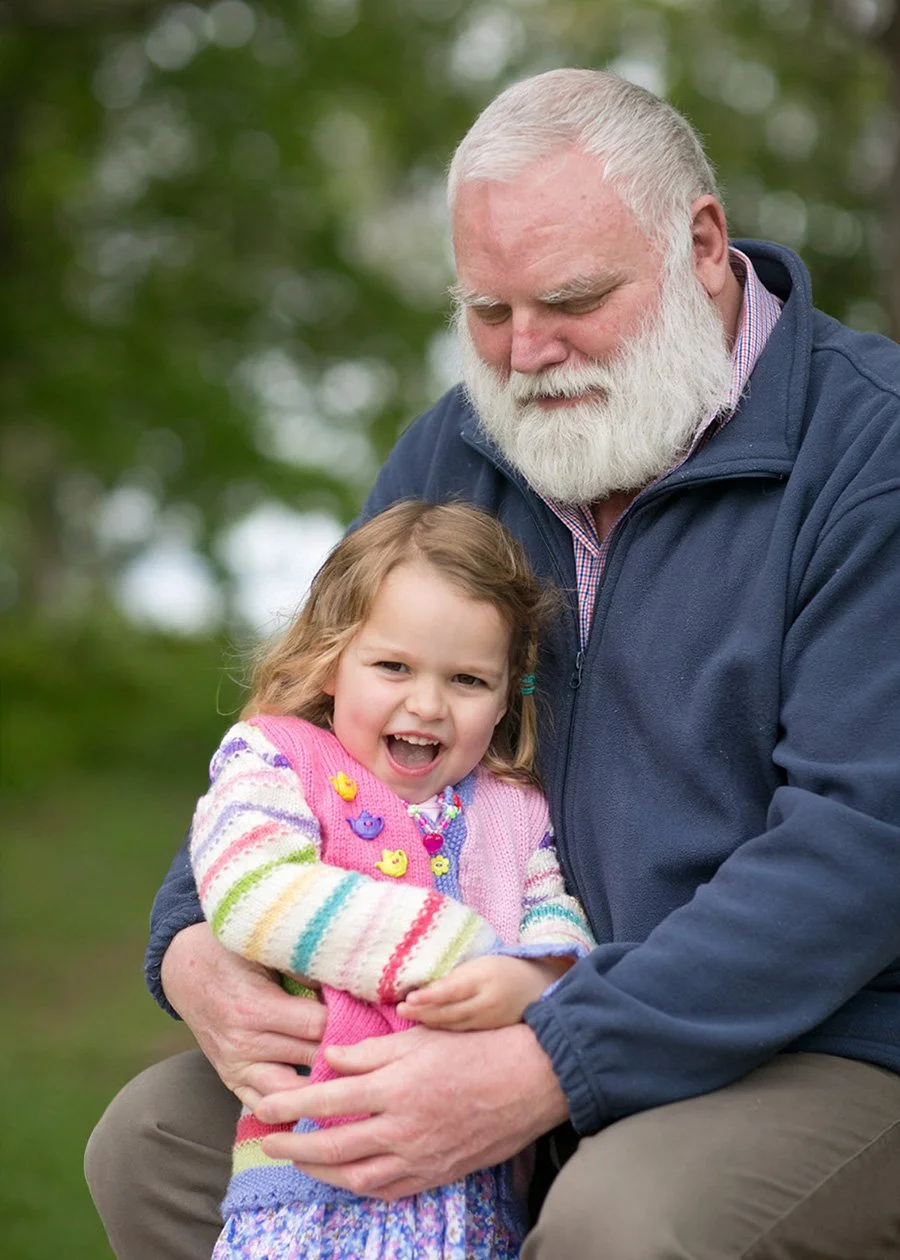 Grandfather embracing young granddaughter in park