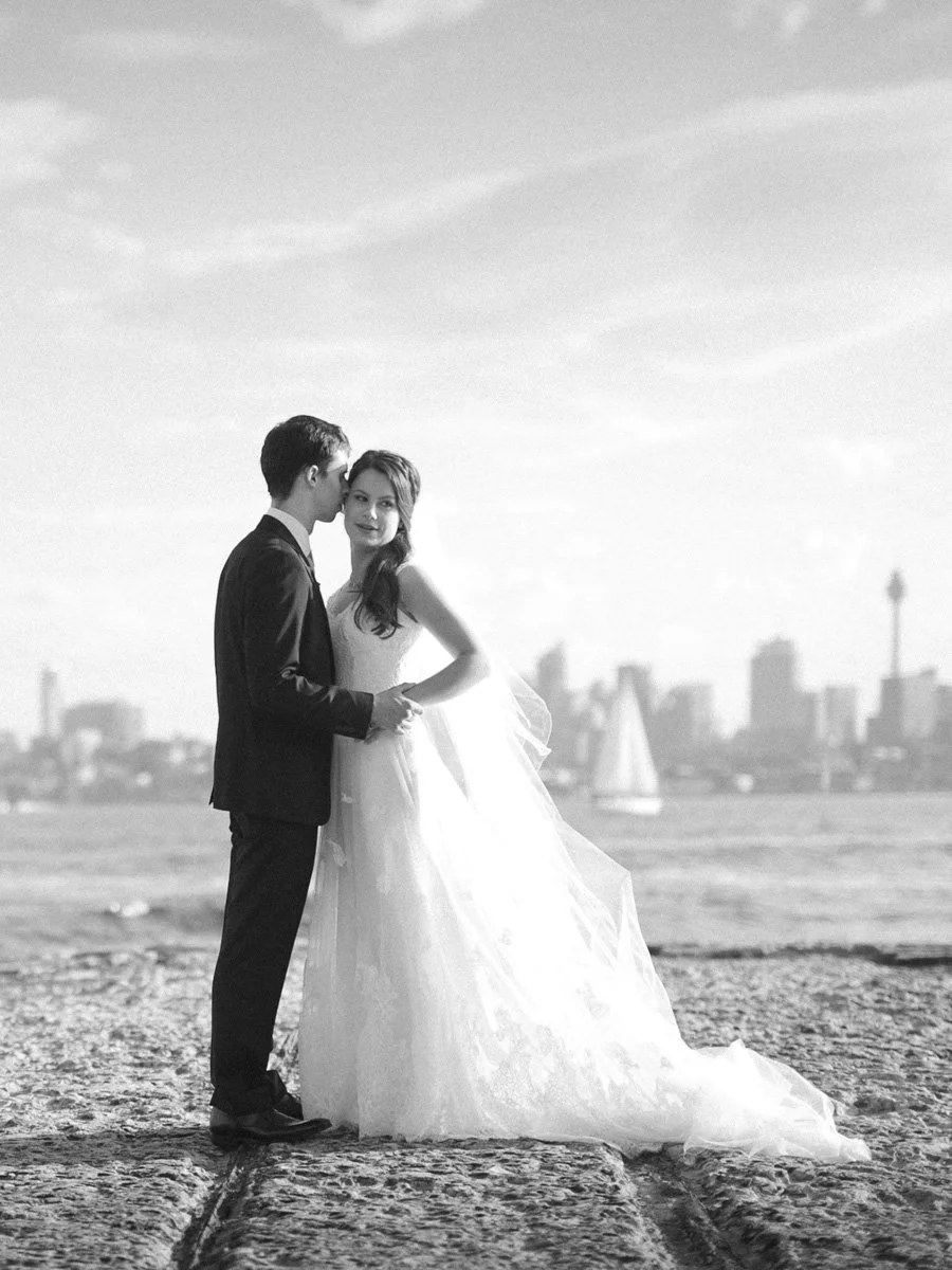 Bride and groom standing on the pier with Sydney Harbour Bridge in the distance, Bradleys Head Mosman