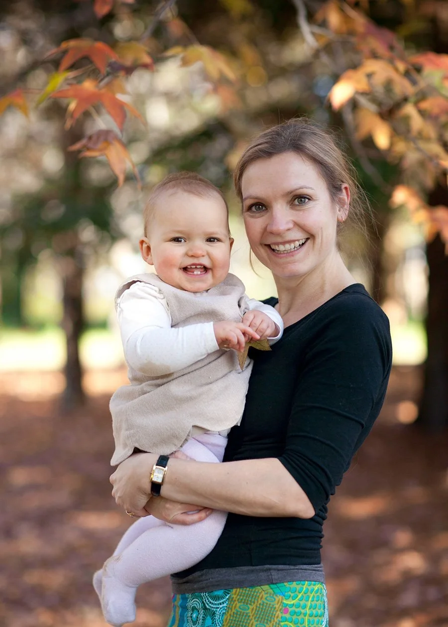 Mother holding baby in autumn leaves park